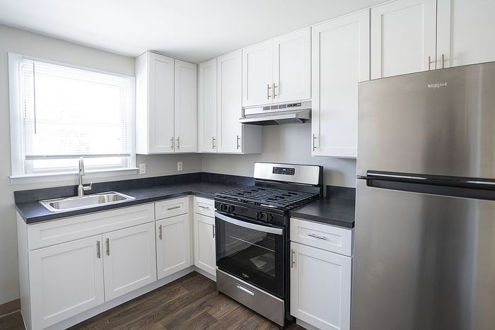 Bright and modern kitchen boasting sleek white cabinetry, stainless steel appliances, and elegant dark countertops.