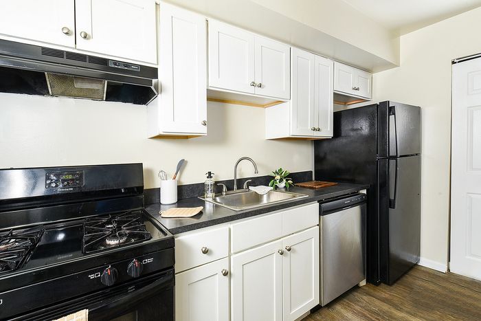 Sleek modern kitchen with white cabinetry, black appliances, and elegant wooden flooring, perfect for stylish living.