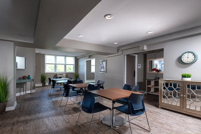 Chic communal area with modern wood flooring, stylish tables, and natural light from large windows.