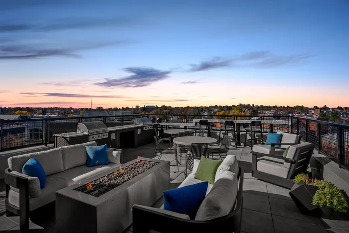 Luxurious rooftop terrace with cozy seating, modern fire pit, and scenic sunset views, perfect for evening relaxation and entertainment.