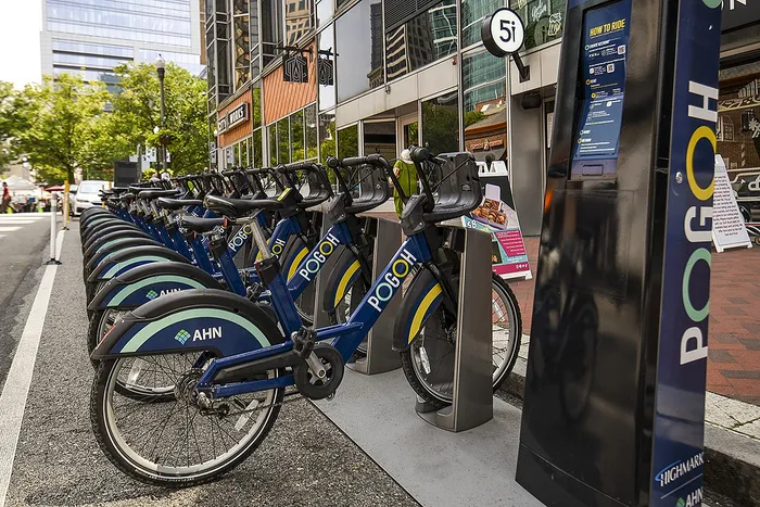 Vibrant urban bike rental station featuring a fleet of blue Pogoh bicycles lined up and ready for an eco-friendly city adventure.