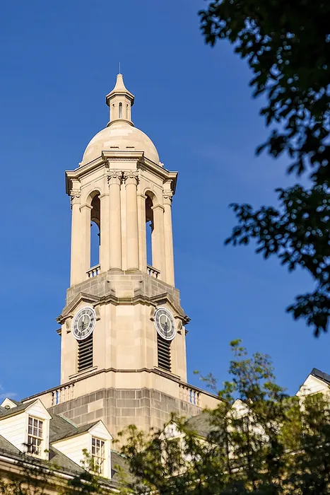 Elegant architectural tower with clock faces and intricate design set against a clear blue sky.