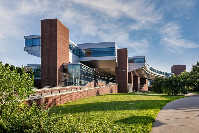 Modern architectural marvel with sleek glass and brick design, showcasing expansive windows and lush green surroundings.