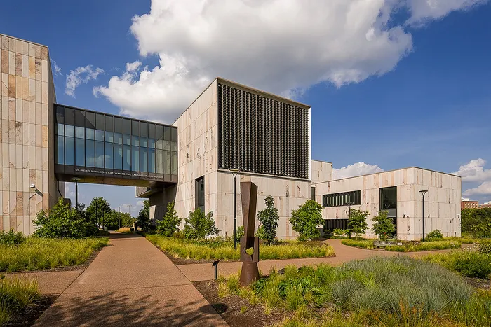 Contemporary architectural marvel with expansive pathways and lush greenery under a vibrant sky.