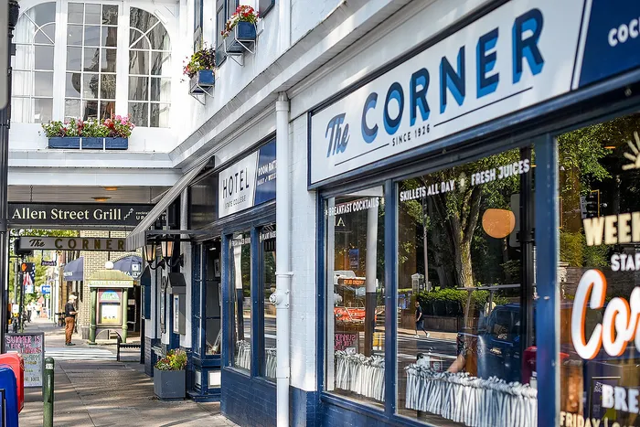 Charming street view showcasing vibrant storefronts of a historical hotel and cafe with colorful flower boxes and inviting signage.