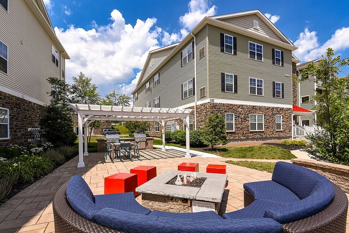 Inviting outdoor patio with a modern fire pit, stylish seating, and vibrant atmosphere set against charming residential architecture.