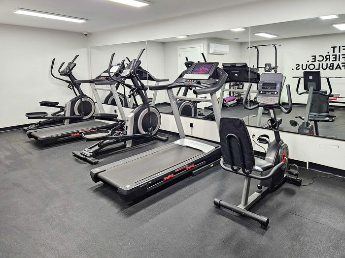 Modern apartment gym with state-of-the-art treadmills and exercise bikes, featuring a sleek mirrored wall for a spacious feel.
