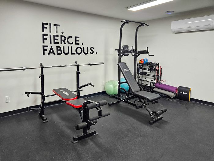Modern apartment gym with motivational wall art, featuring diverse workout equipment including a weight bench and resistance bands.
