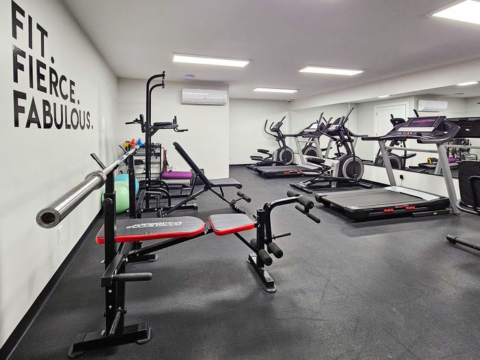 Modern fitness center featuring state-of-the-art exercise equipment, motivational wall art, and pristine flooring for an energizing workout experience.
