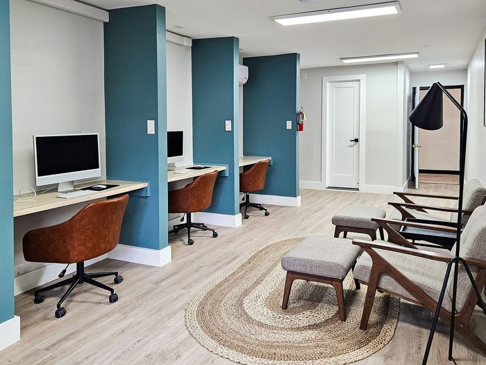 Modern co-working space with sleek computer stations, comfortable leather chairs, and a stylish lounge area for relaxation.
