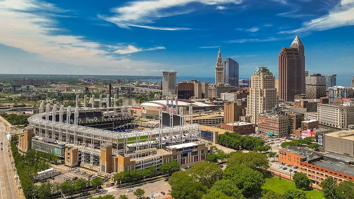 Vibrant urban skyline with a modern stadium and towering skyscrapers under a clear blue sky, showcasing the dynamic essence of city life.
