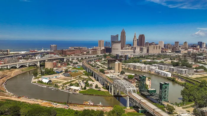 Breathtaking aerial view of a vibrant city skyline with modern high-rises and expansive waterway bridges under a clear blue sky, showcasing dynamic urban living.