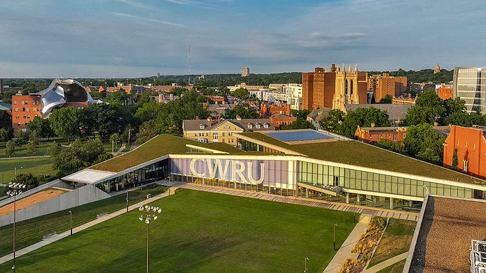Modern university campus with a unique architectural design, green rooftop, and lush surroundings, showcasing an inviting educational environment.