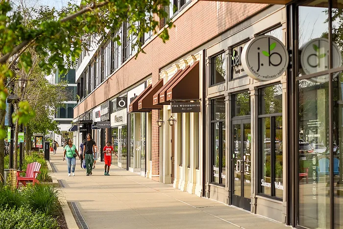 Vibrant urban street lined with charming shops and lush greenery, creating a welcoming and lively neighborhood atmosphere.