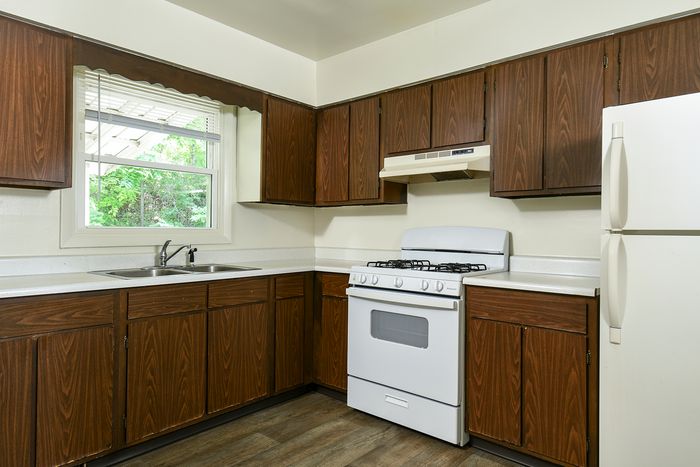 Cozy kitchen with warm wooden cabinets, sleek countertops, and a bright window view, ideal for culinary creativity and entertaining.