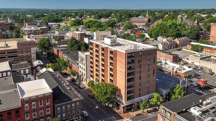 Vibrant aerial view of a bustling town featuring a prominent apartment building surrounded by lush greenery, showcasing a dynamic urban landscape.