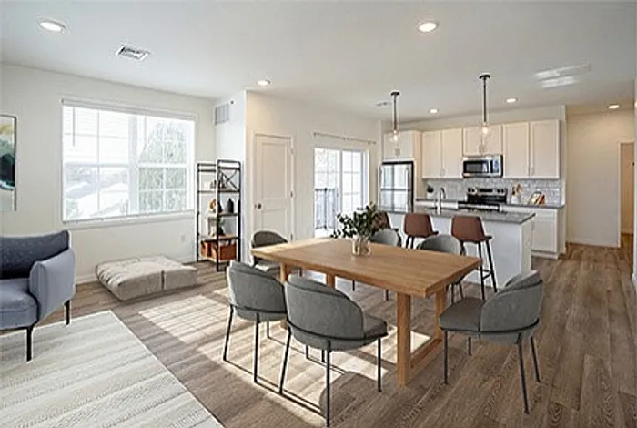 Bright and modern open-concept living space featuring a chic dining area, cozy seating, and a sleek kitchen with white cabinetry and stainless steel appliances.