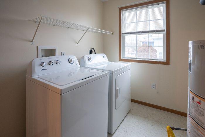 Bright and airy laundry room featuring modern washer and dryer with large window for natural light.
