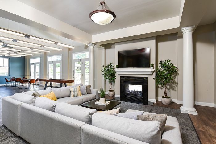Elegant living room with a cozy sectional sofa, stylish fireplace, and wall-mounted TV, accented by large windows and modern decor.