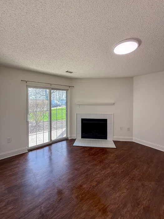 Inviting living room with elegant hardwood flooring, cozy fireplace, and sliding glass doors leading to a lush outdoor view.