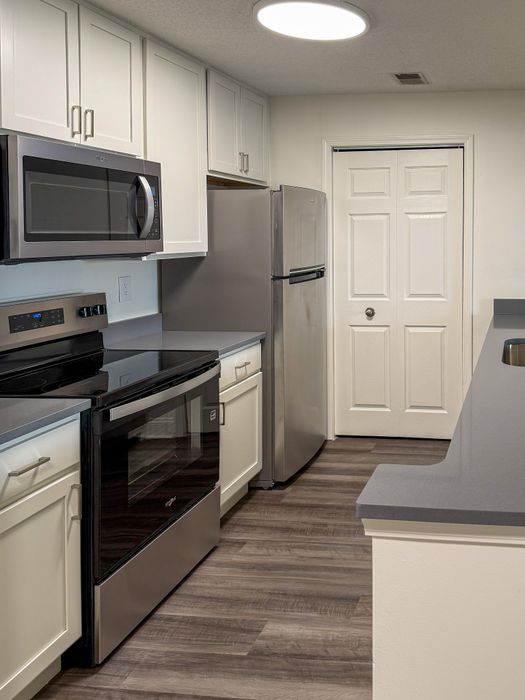 Modern kitchen with sleek stainless steel appliances, elegant cabinetry, and stylish wood flooring.