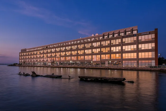 Elegant waterfront building at dusk, reflecting serene waters, offering premium leasing opportunities.