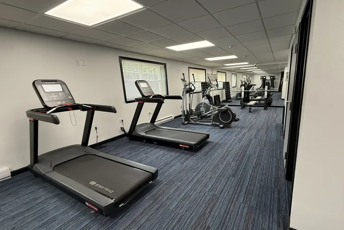 Modern fitness center equipped with state-of-the-art treadmills, elliptical machines, and weight stations, offering a sleek workout environment.