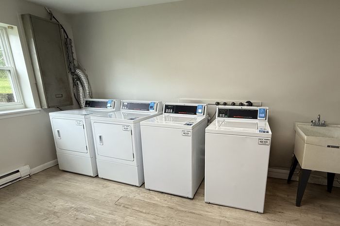 Bright and functional laundry room featuring modern washing machines and dryers, complemented by a utility sink and natural light from a nearby window.