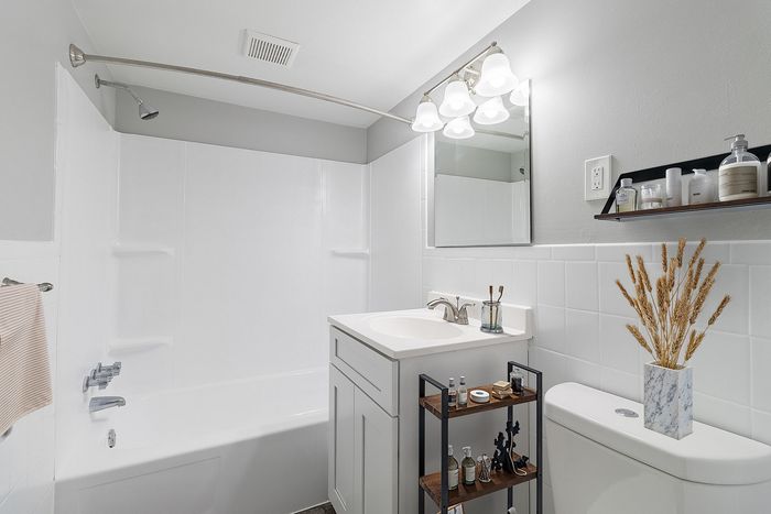 Modern bathroom featuring elegant lighting, sleek white fixtures, and stylish shelving for a clean, sophisticated look.