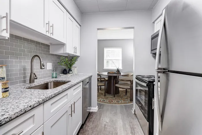 Sleek modern kitchen with granite countertops, stylish cabinetry, and stainless steel appliances leading to a cozy dining area.