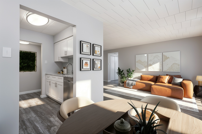 Modern apartment interior with open-concept living space, featuring a cozy tan sofa, stylish wall art, and a sleek kitchen with white cabinetry.