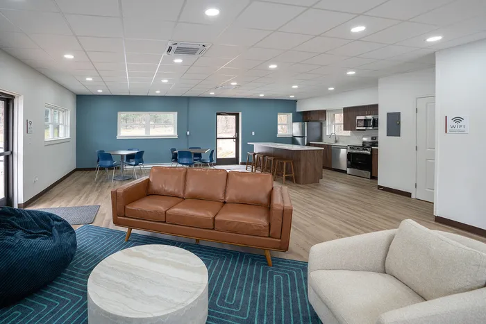 Modern open-concept living space featuring a stylish brown leather sofa, plush seating, and a spacious kitchen with a breakfast bar. Perfect for elegant living and entertaining.