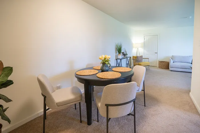 Inviting open-plan dining and living area with cozy seating, stylish decor, and soft carpet flooring.