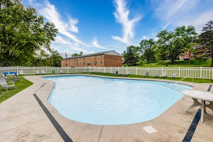 Inviting outdoor pool area surrounded by lush greenery and modern loungers, perfect for relaxing and enjoying a sunny day.