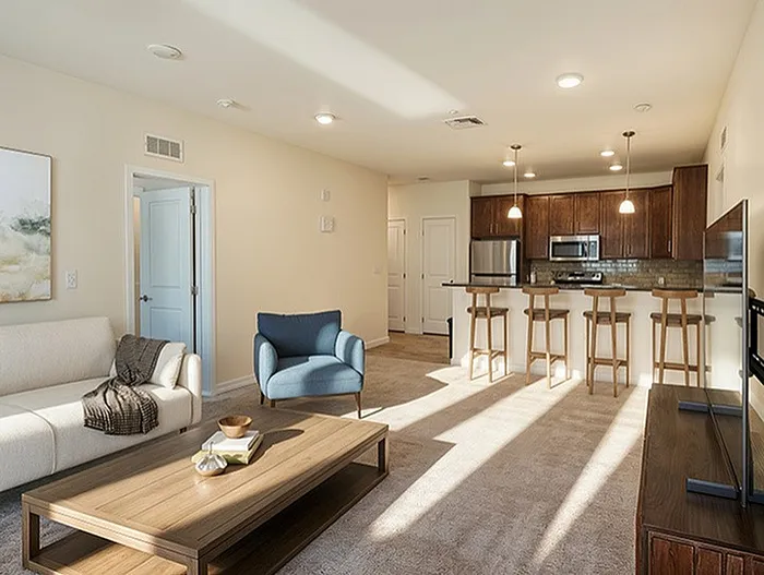 Inviting living room with plush carpeting, elegant decor, and abundant natural light from a large window, leading into a cozy bedroom.