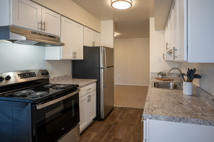 Sleek modern kitchen featuring stainless steel appliances, ample cabinetry, and elegant countertops in a cozy apartment setting.