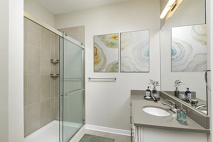 Modern bathroom with sleek glass shower, elegant countertop, and artistic wall decor.