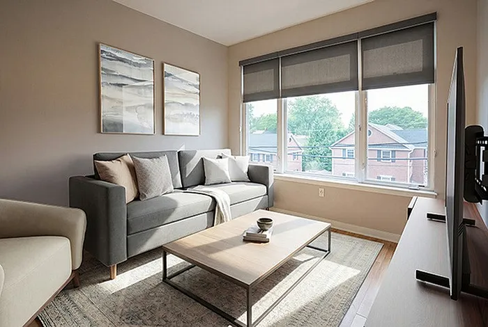 Bright and inviting living room with modern gray sofa, stylish coffee table, and large windows offering serene neighborhood views.
