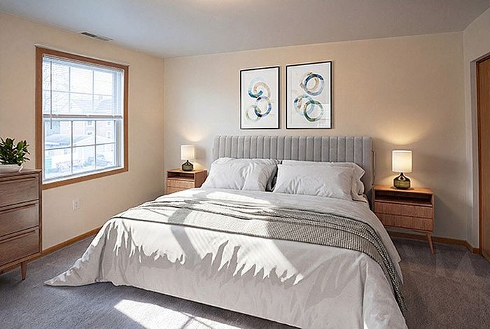 Inviting bedroom with a plush king-size bed, modern furnishings, and warm natural light from a large window.