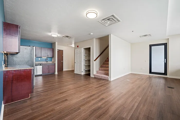 Contemporary open-concept living space with elegant hardwood floors, modern kitchen, and loft-style staircase.