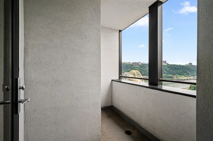 Cozy balcony with stunning views of lush green hills and a striking golden bridge under a bright blue sky.