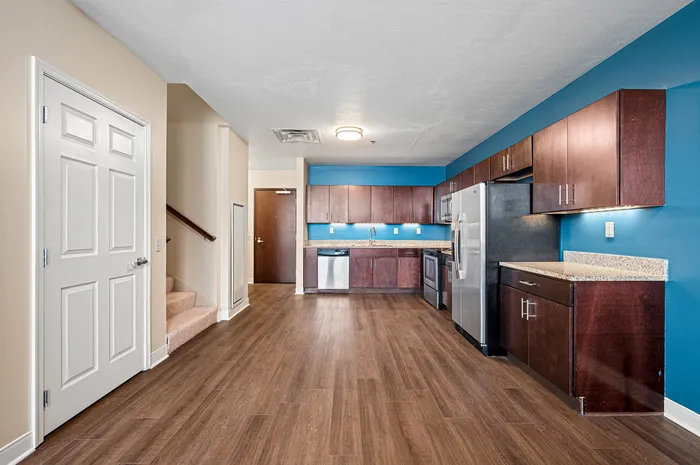 Chic modern kitchen with elegant wood flooring, stainless steel appliances, and vibrant blue accent wall.