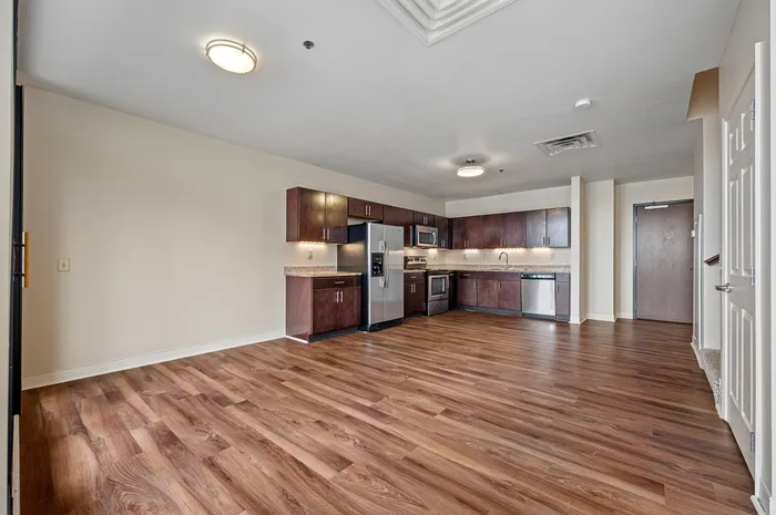 Inviting kitchen space with modern stainless steel appliances, rich wooden cabinets, and elegant hardwood floors.
