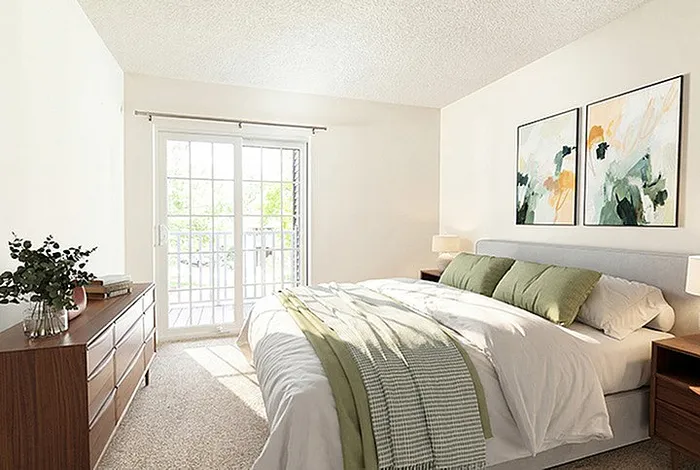 Bright and inviting bedroom with a comfortable bed, modern wooden dresser, and artfully decorated walls, featuring ample natural light from the sliding glass doors.