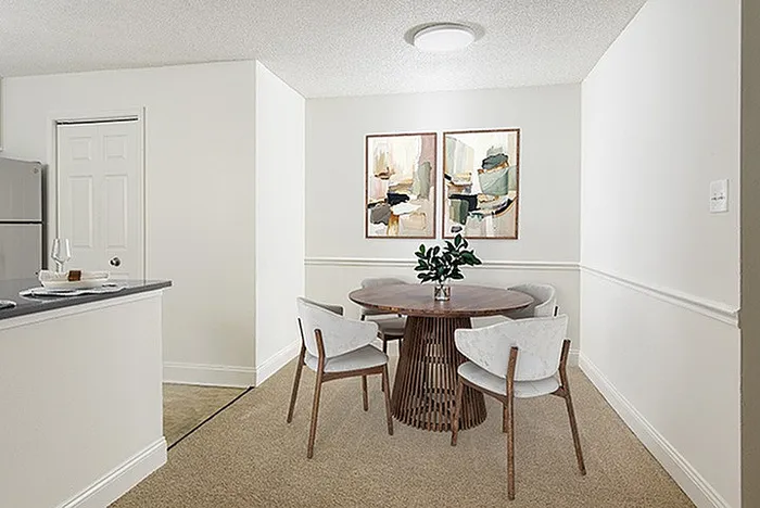 Cozy dining area with modern round table, stylish chairs, and chic artwork, adjacent to a sleek kitchen space.