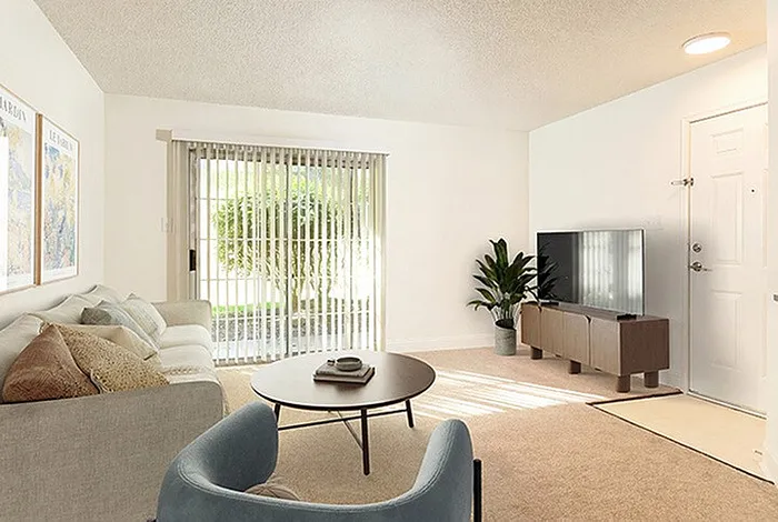 Bright and inviting living room featuring a cozy sofa, elegant coffee table, and large flat-screen TV with natural light streaming through sliding glass doors.
