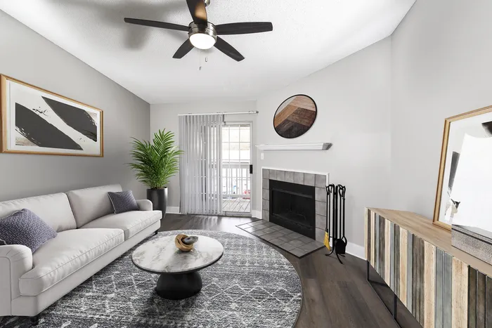 Inviting living room with modern decor, featuring a plush sofa, stylish marble coffee table, and elegant fireplace, complemented by a chic ceiling fan and natural light from sliding glass doors.