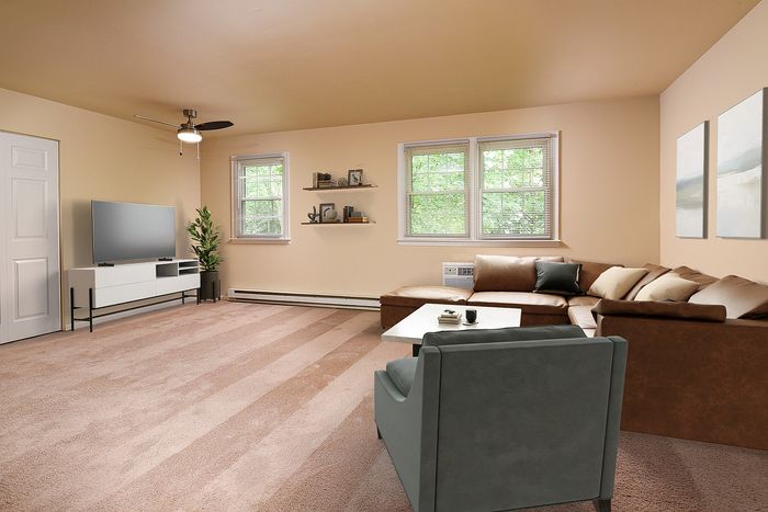 Inviting living room with plush carpet, stylish sectional sofa, and modern entertainment center, bathed in natural light from large windows.