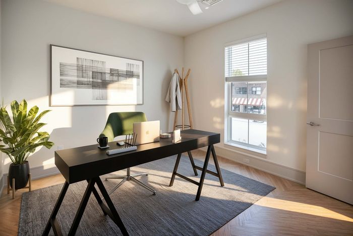 Bright home office with a modern desk, green chair, and elegant decor, featuring natural light from a large window.