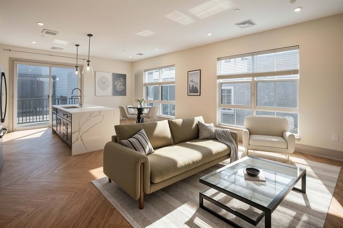 Bright and airy living space with modern open kitchen, elegant furniture, and large windows bringing in natural light.